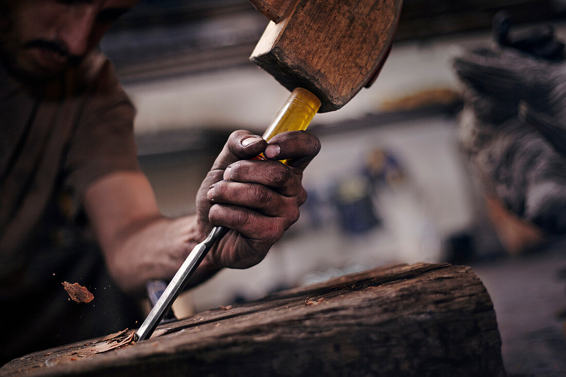 Blacksmith chiselling wood with tool