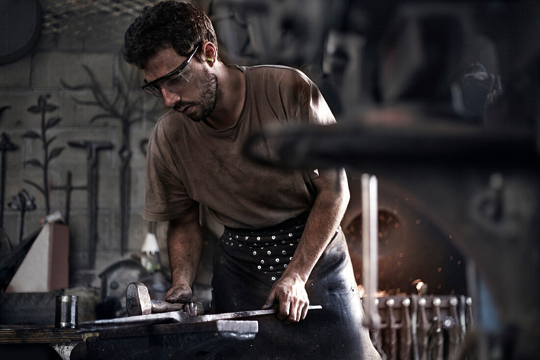 Blacksmith hammering iron at anvil