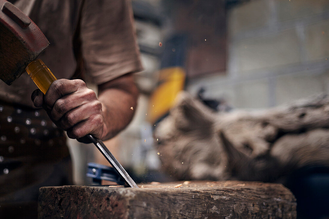 Blacksmith chiselling wood in workshop