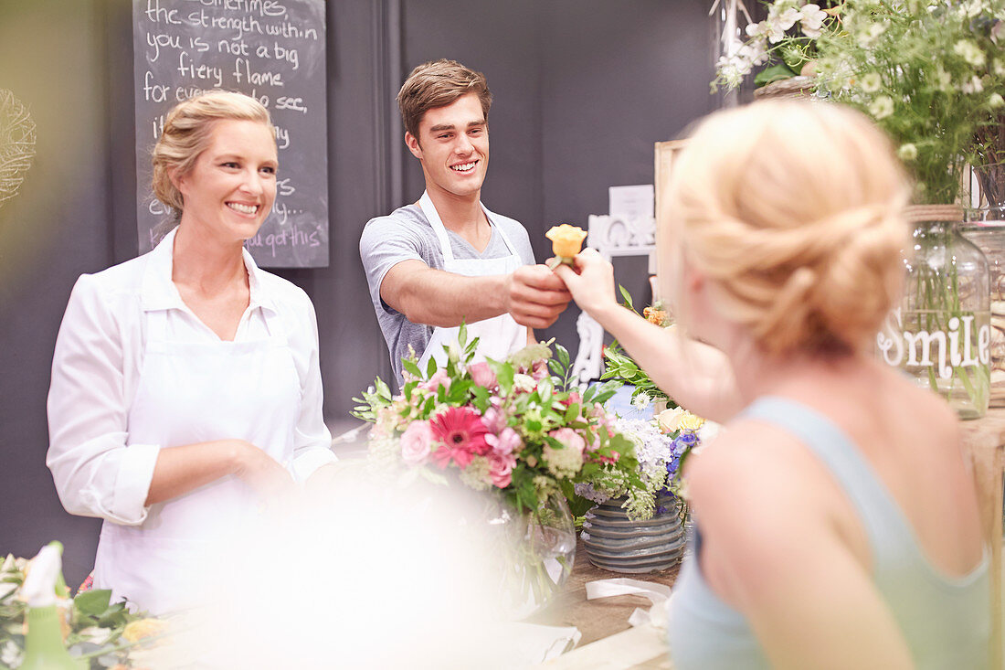 Florist giving woman rose in flower shop