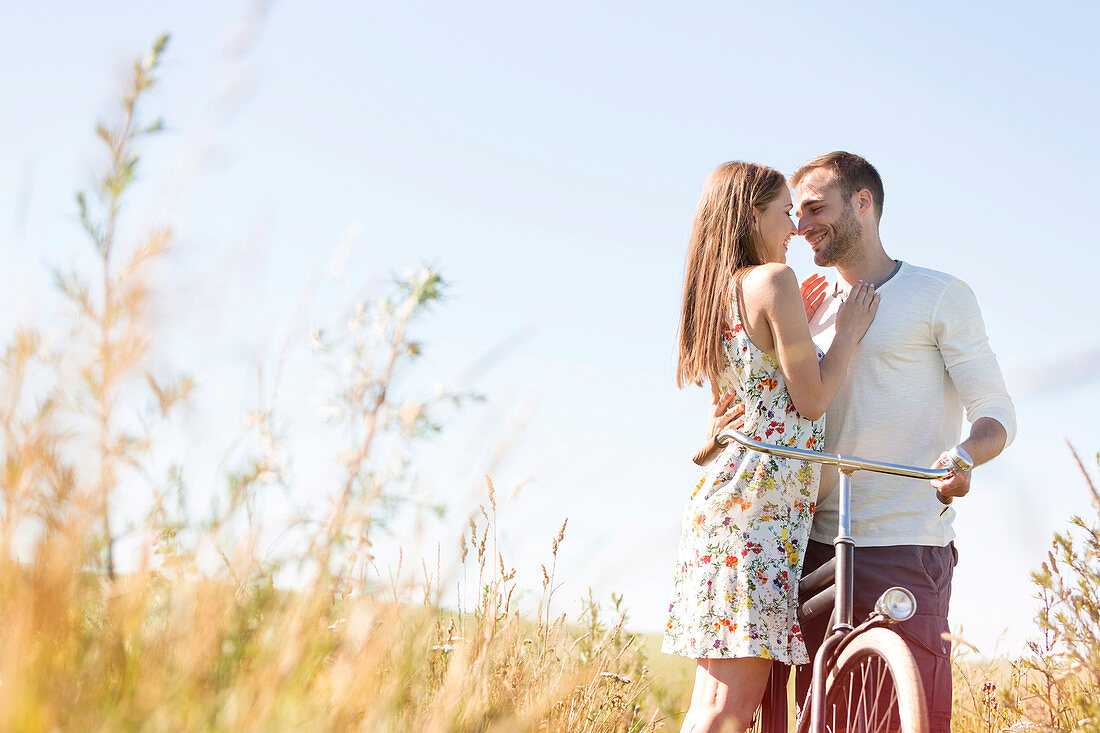 Couple with bike hugging in rural field