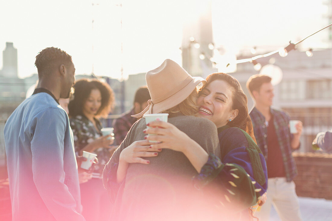 Young women hugging at rooftop party