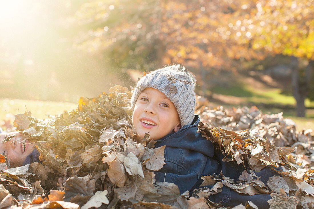 Portrait Boys covered in autumn leaves