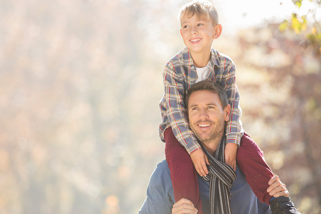 Smiling father carrying son on shoulders