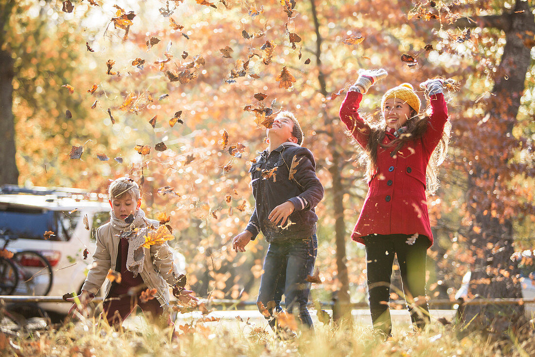 Boys and girl throwing autumn leaves