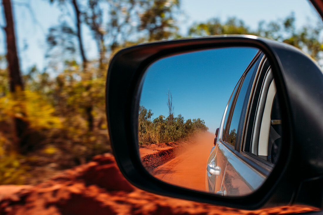 Dust cloud in side-view mirror of car