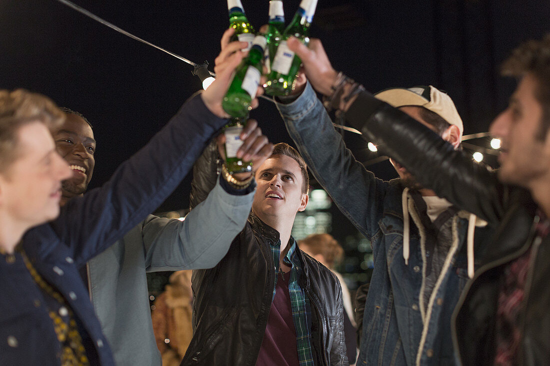 Young men toasting beer bottles at party