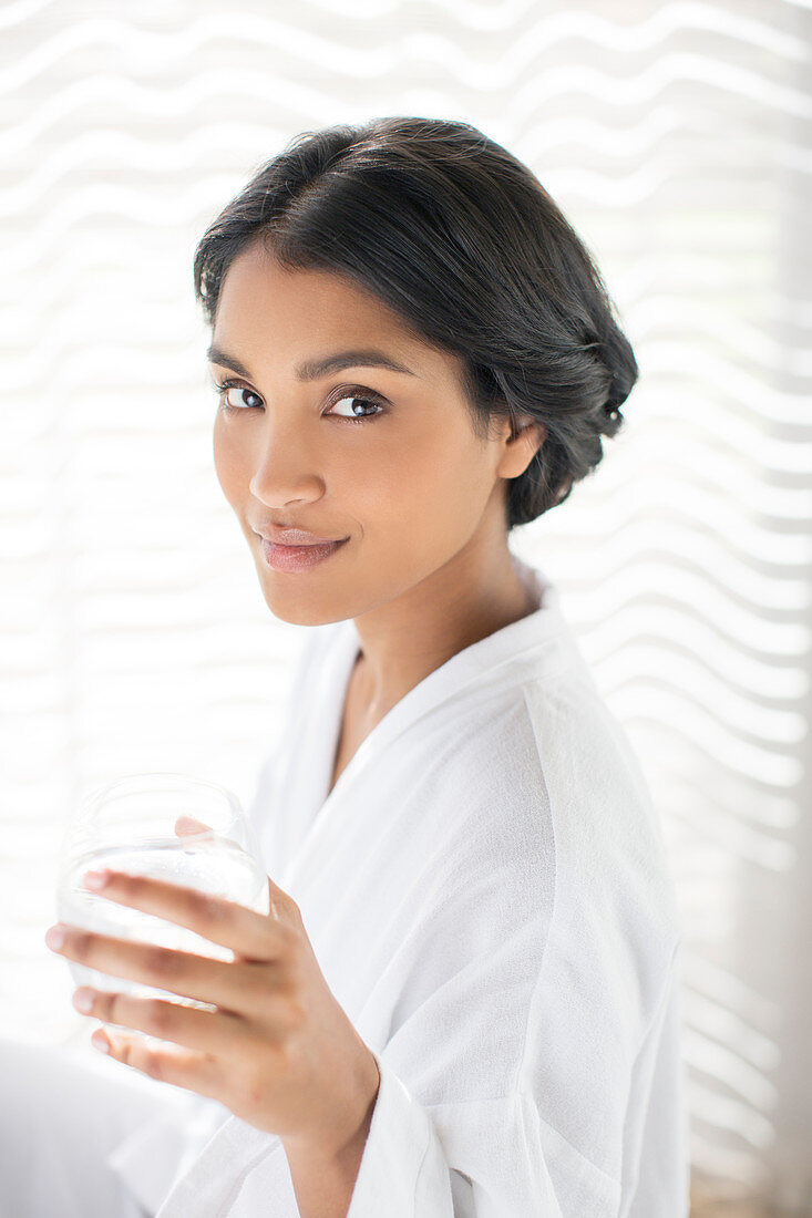 Woman in bathrobe drinking water