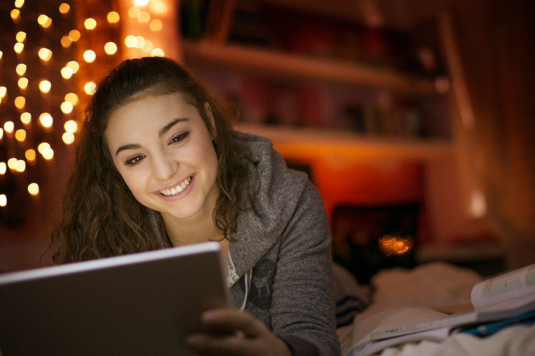 Smiling teenage girl using tablet on bed