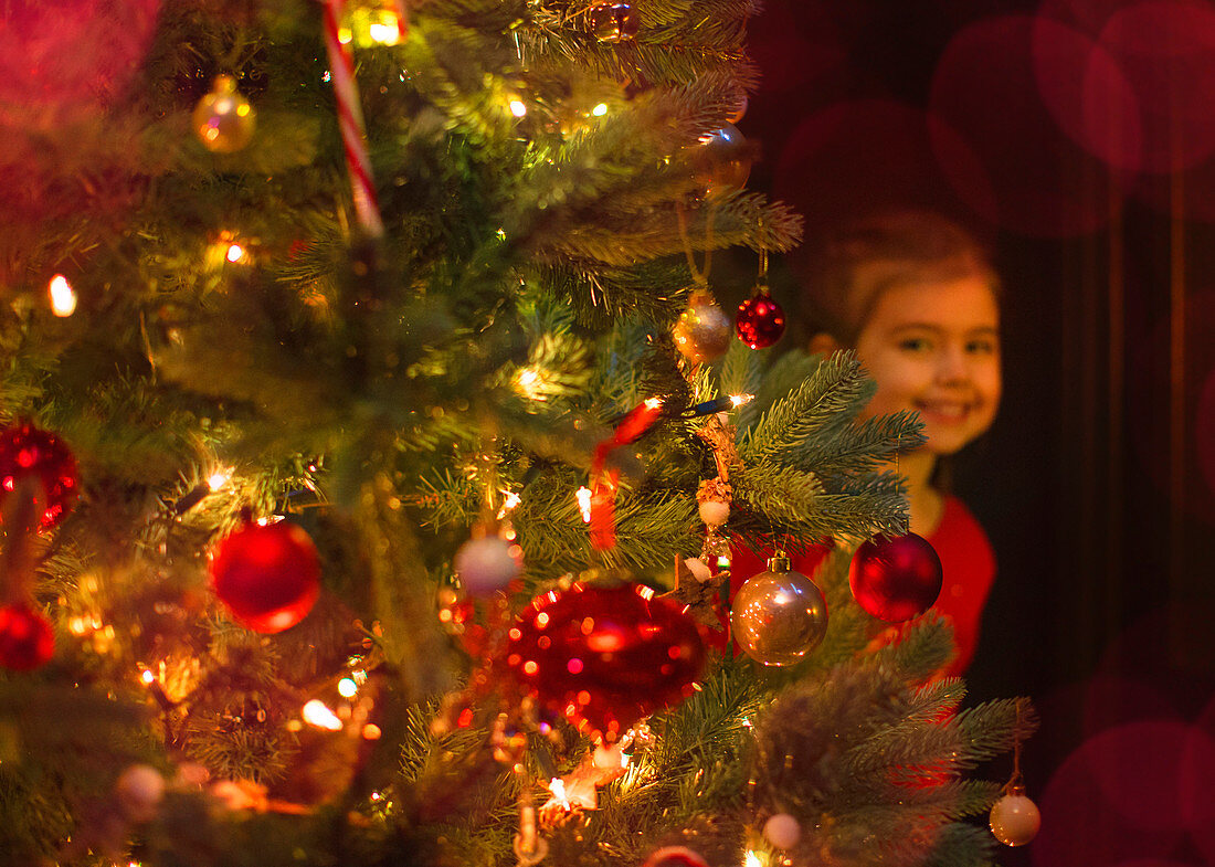 Girl hiding behind Christmas tree