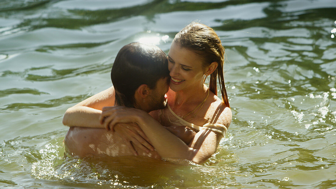 Couple hugging and swimming in sunny lake