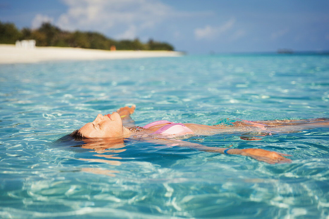 Serene woman floating in tropical ocean