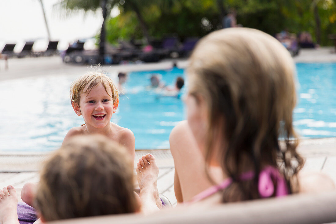 Mother and sons relaxing at poolside