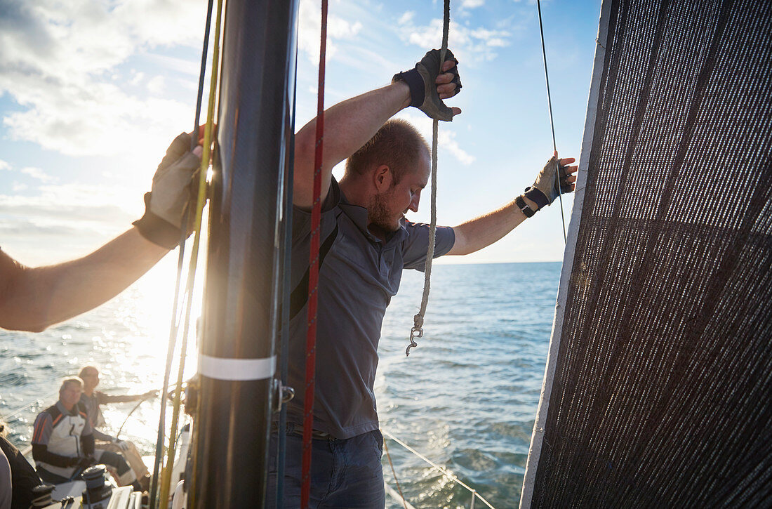 Man adjusting sailing rigging on sailboat