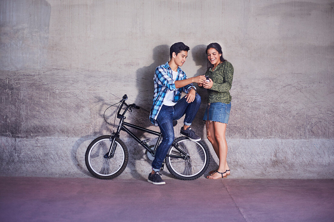 Teenage couple with BMX bicycle texting
