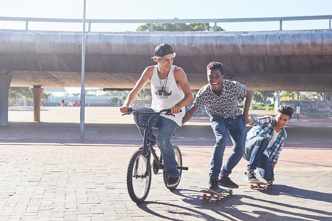 Boys riding BMX bicycle and skateboarding