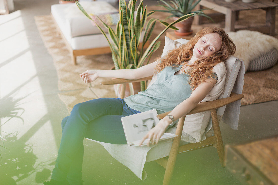 Woman with book napping in armchair