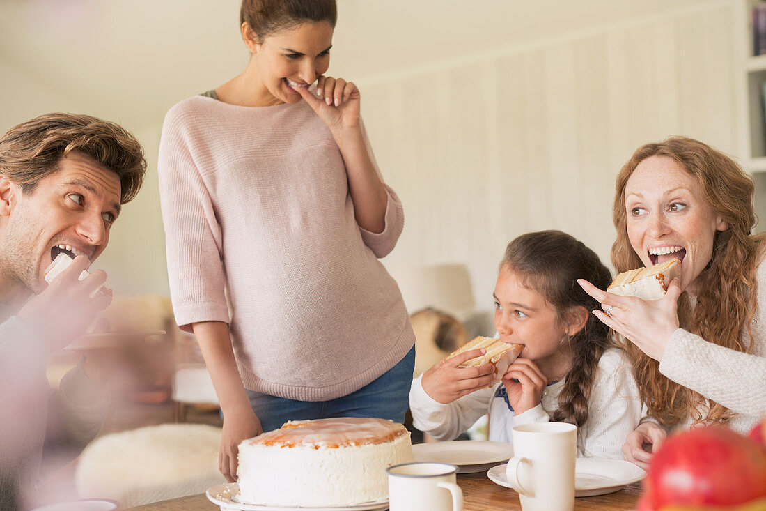 Enthusiastic family eating cake at table