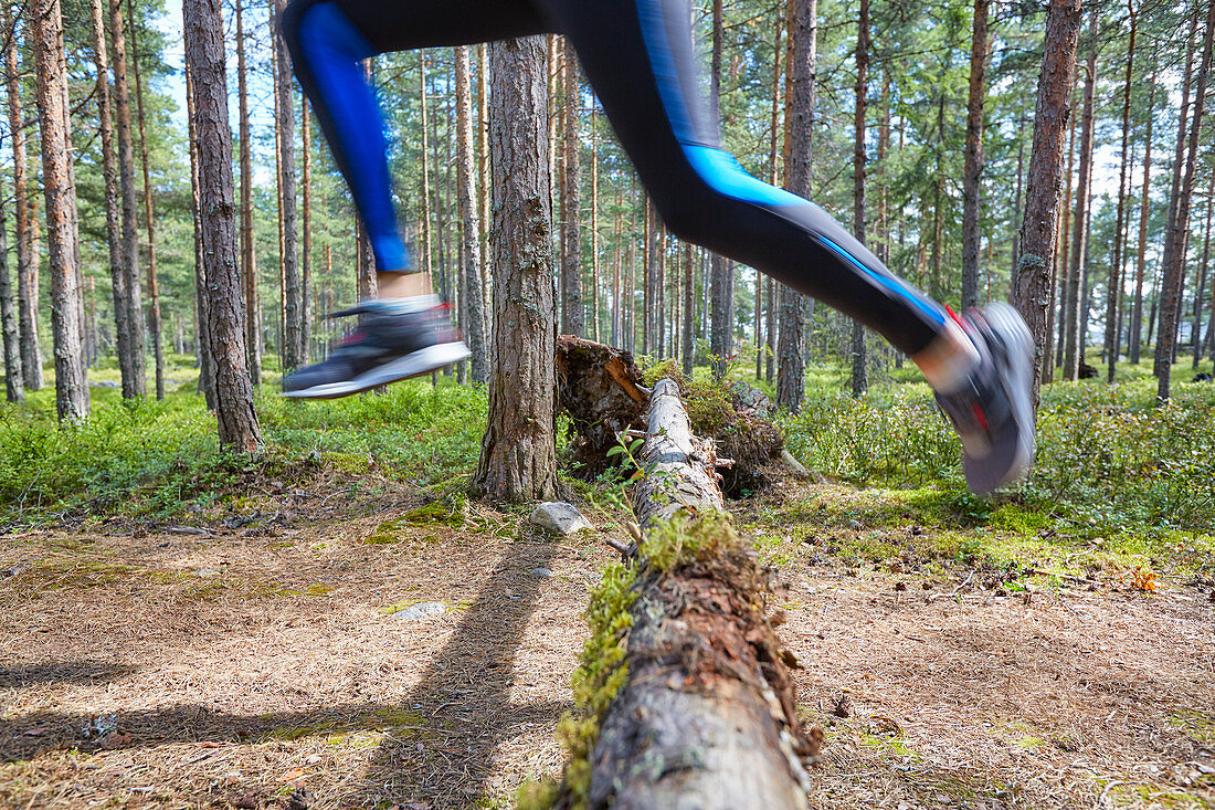 Runner jumping over fallen log