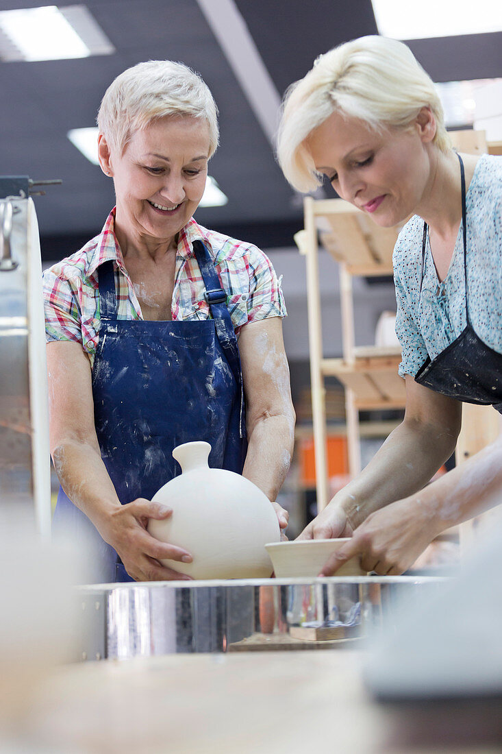 Women placing pottery in kiln in studio