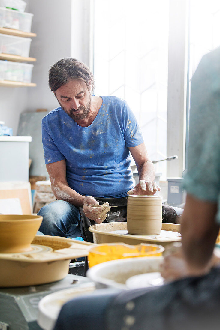 Mature man using pottery wheel in studio