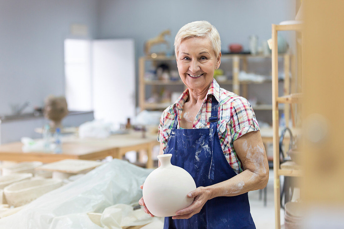 Senior woman holding pottery vase