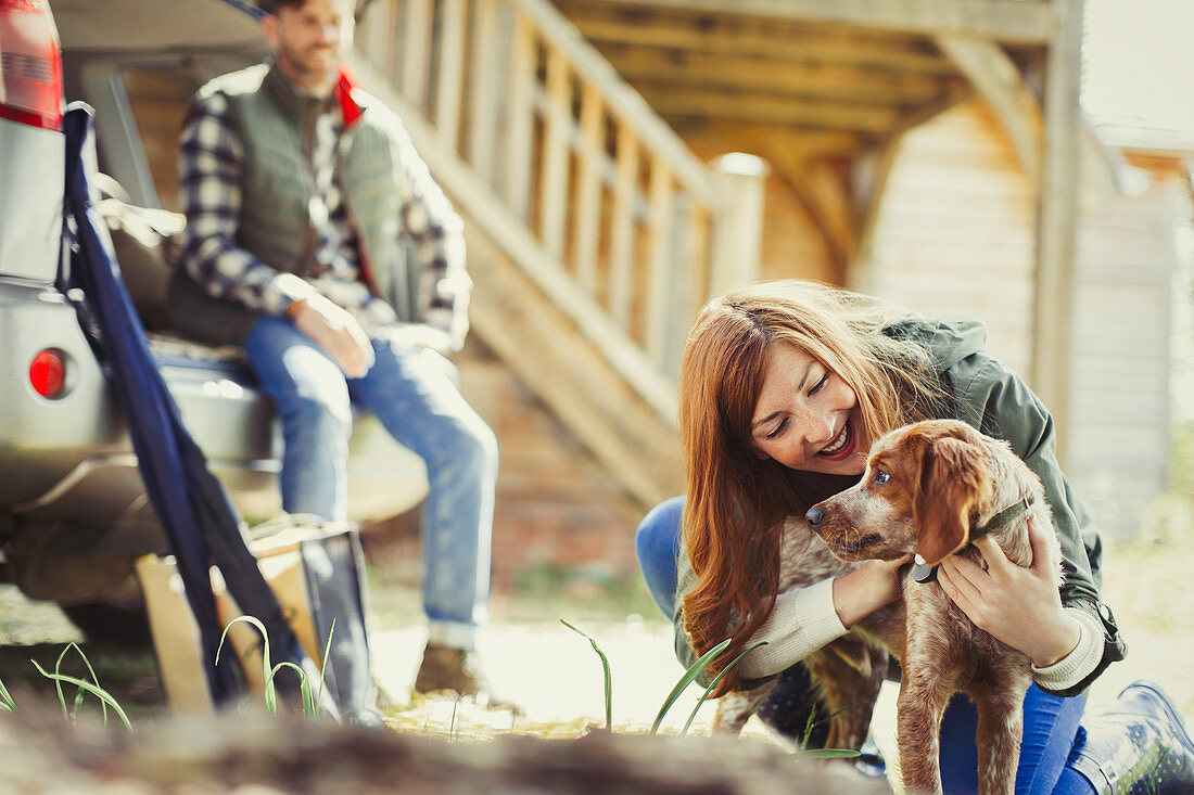 Woman petting dog outside cabin