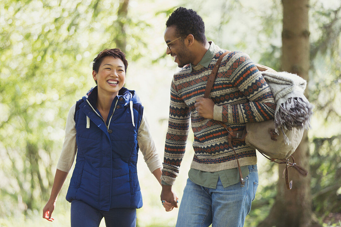 Couple holding hands hiking in woods