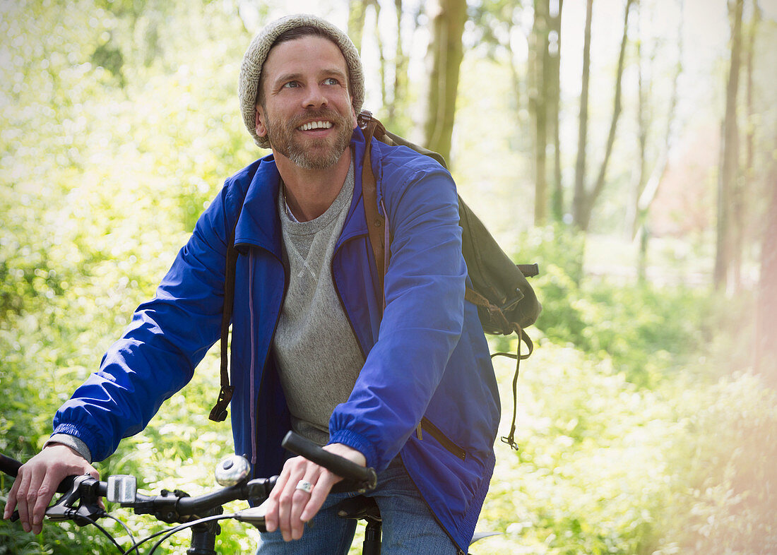 Smiling man mountain biking in woods