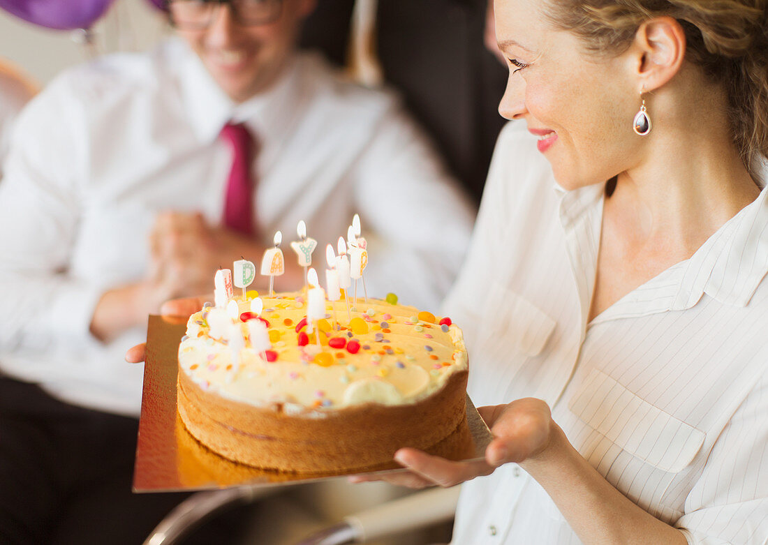Businesswoman holding birthday cake with candles