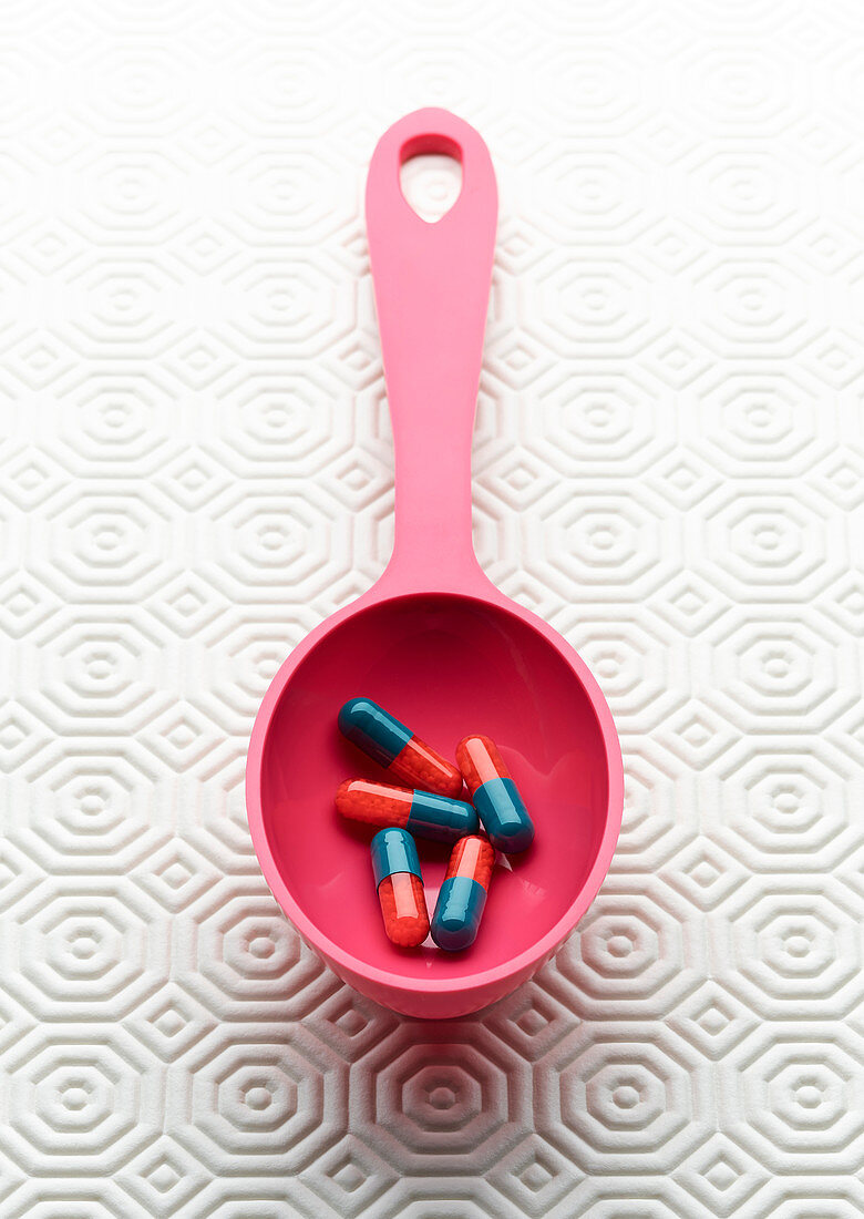 Medical capsules in pink spoon