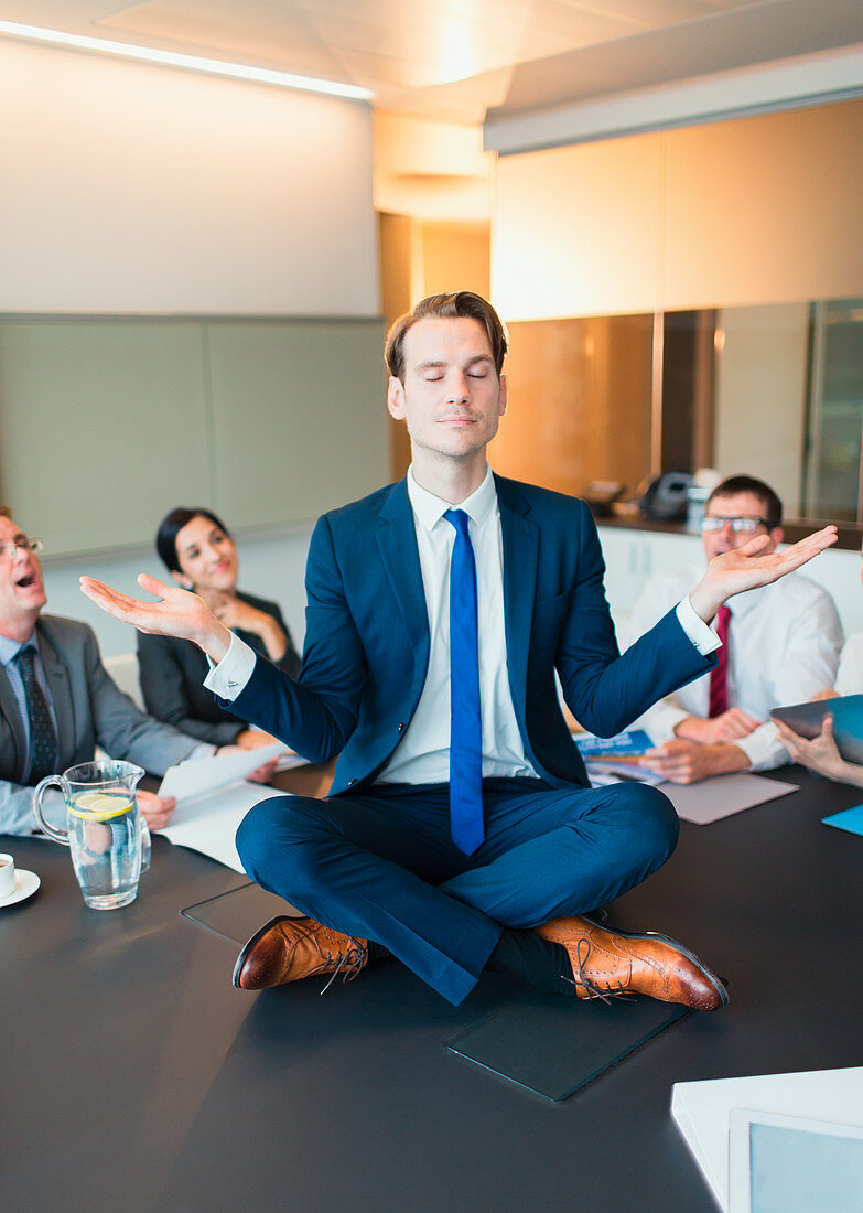 Colleagues watching businessman meditating