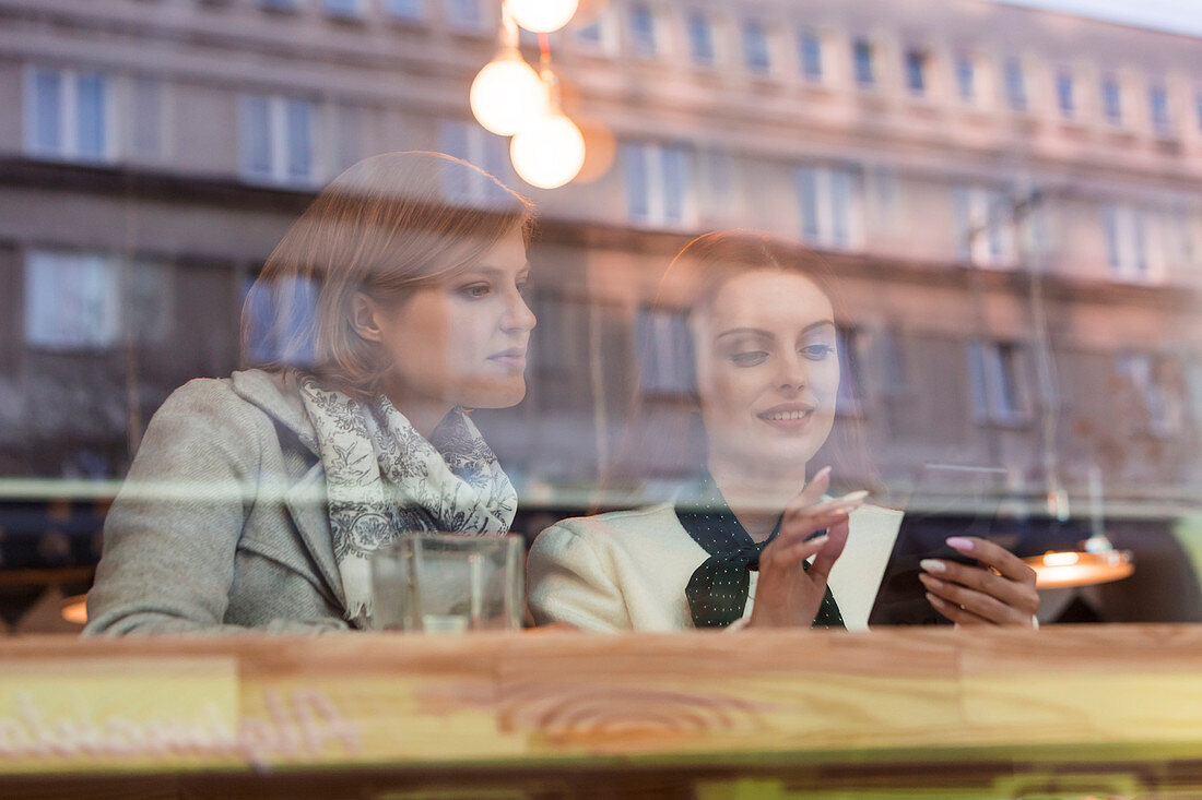 Businesswomen using cell phone at cafe window