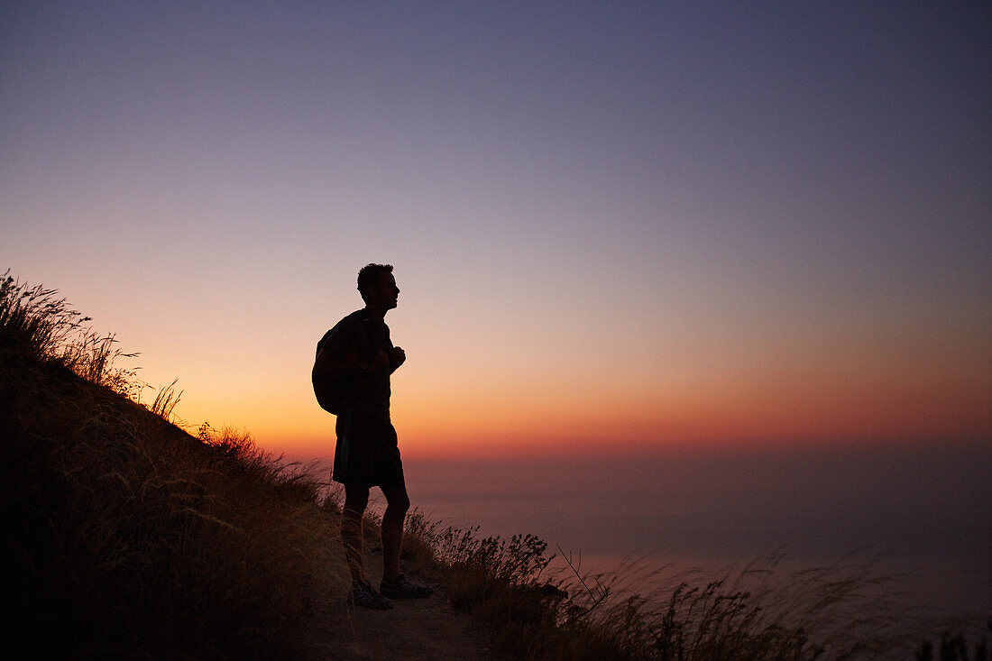 Silhouette of male hiker overlooking ocean