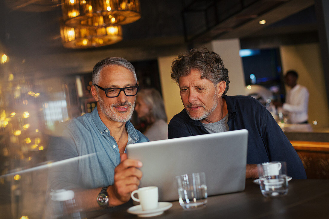 Men using laptop at restaurant