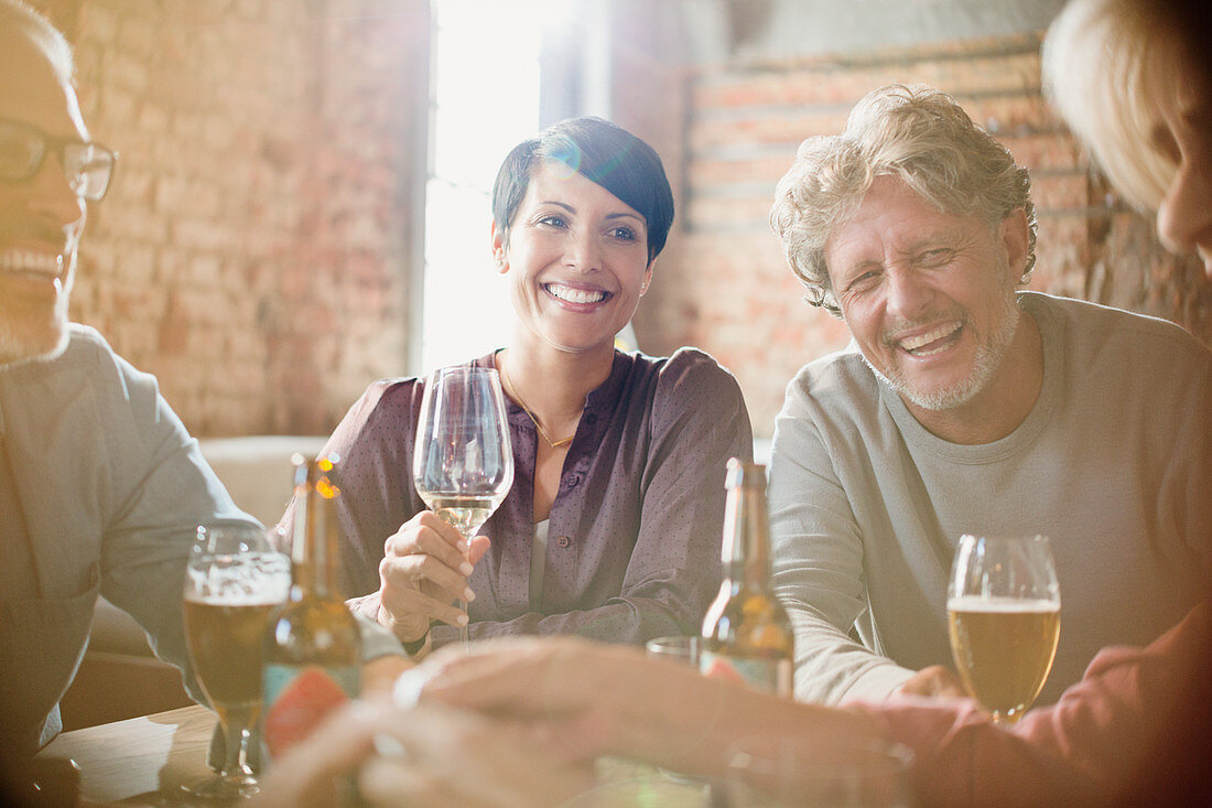 Laughing couples drinking white wine and beer