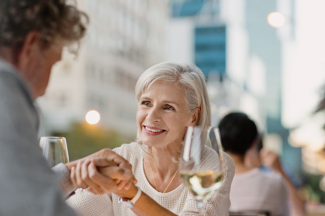 Senior couple holding hands drinking white wine