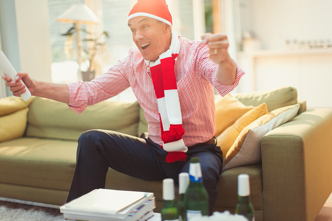 Mature man in hat and scarf watching TV