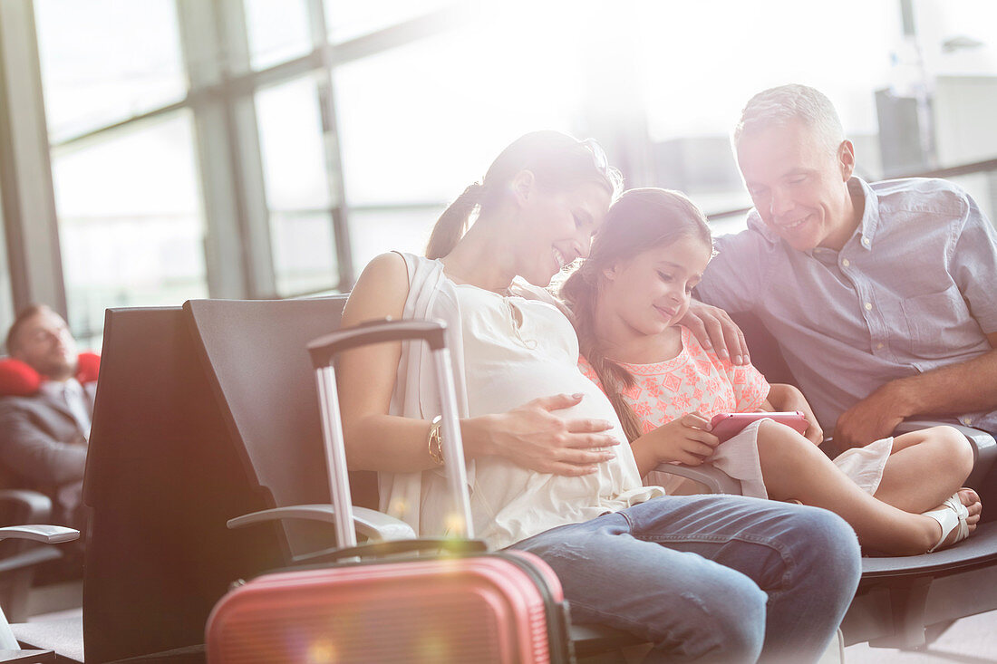 Pregnant family using digital tablet waiting