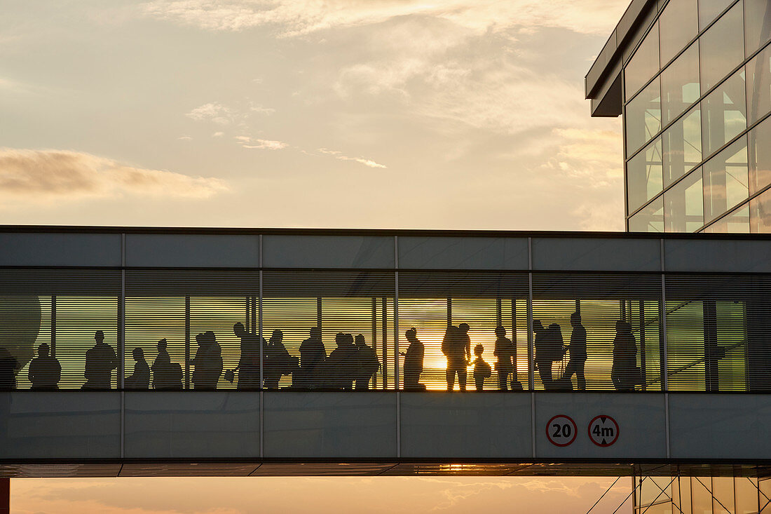 Silhouette people walking in airport sky bridge