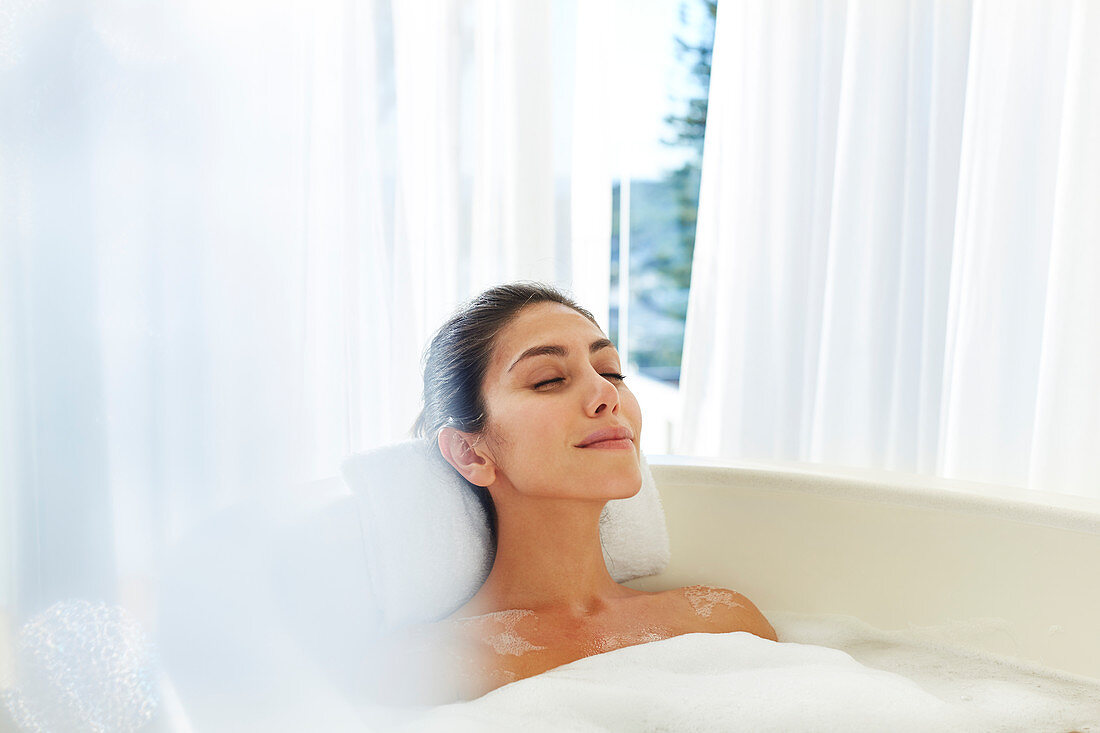 Serene woman enjoying bubble bath with eyes closed