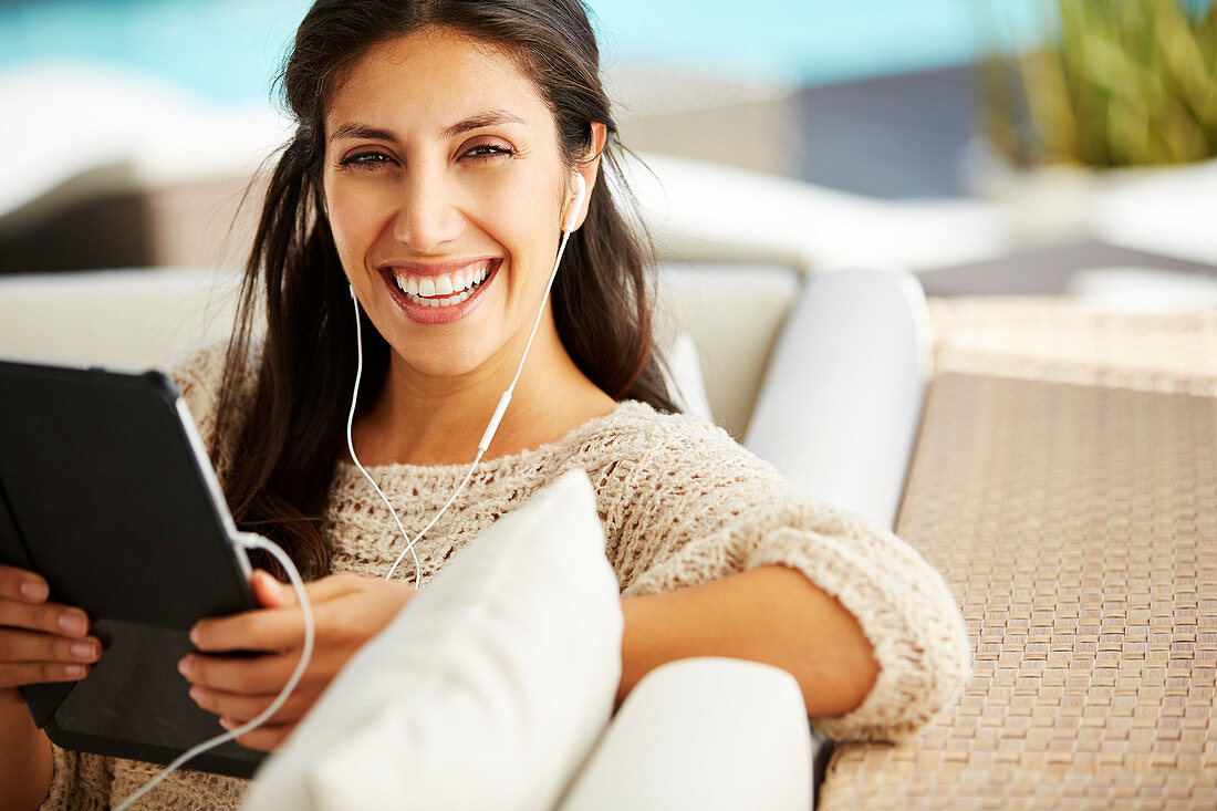 Woman using digital tablet and headphones on sofa