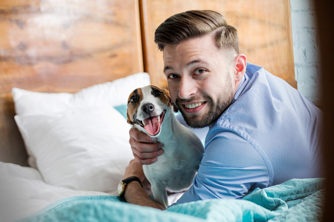 Smiling man petting Jack Russell Terrier dog