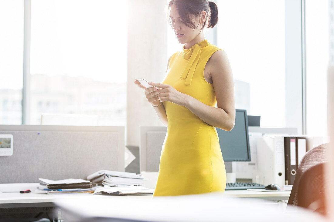 Businesswoman texting with cell phone in office