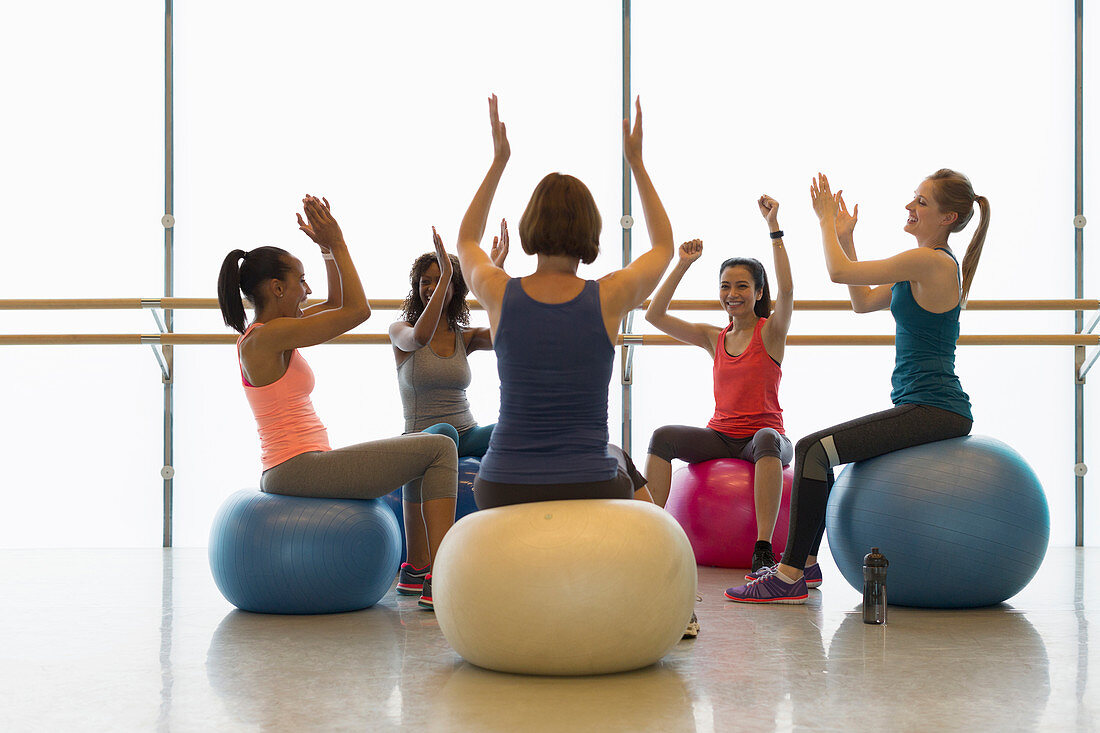 Women on fitness balls cheering and clapping