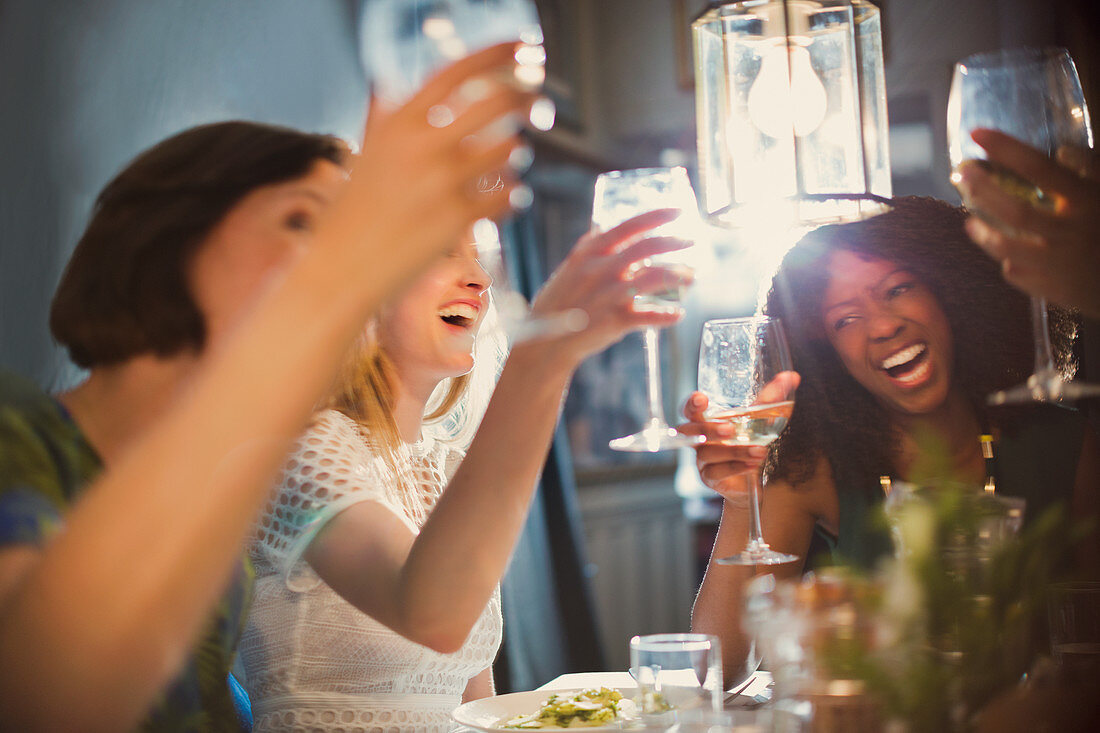 Laughing women friends toasting wine glasses