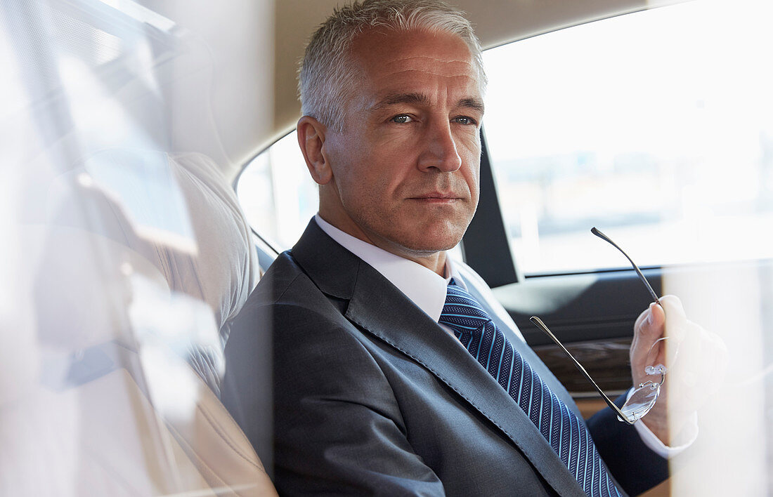 Pensive businessman riding in back seat of car