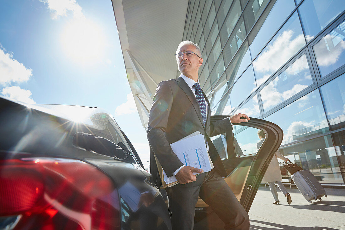 Businessman arriving at airport getting out of car