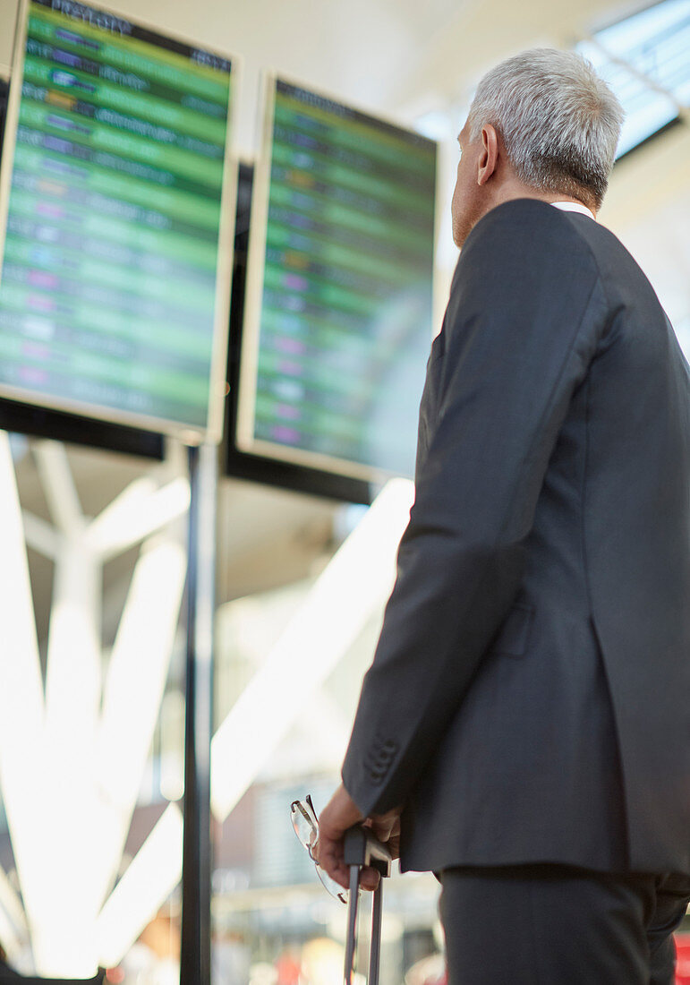 Businessman looking up at airport board
