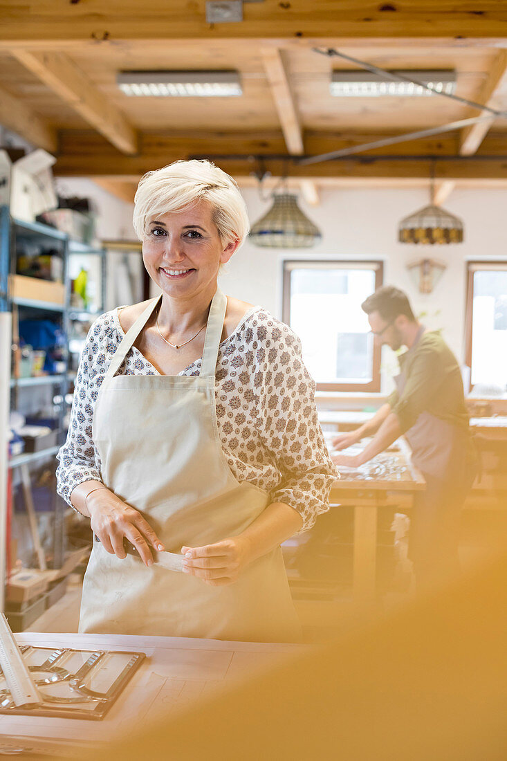 Smiling stained glass artist working in studio